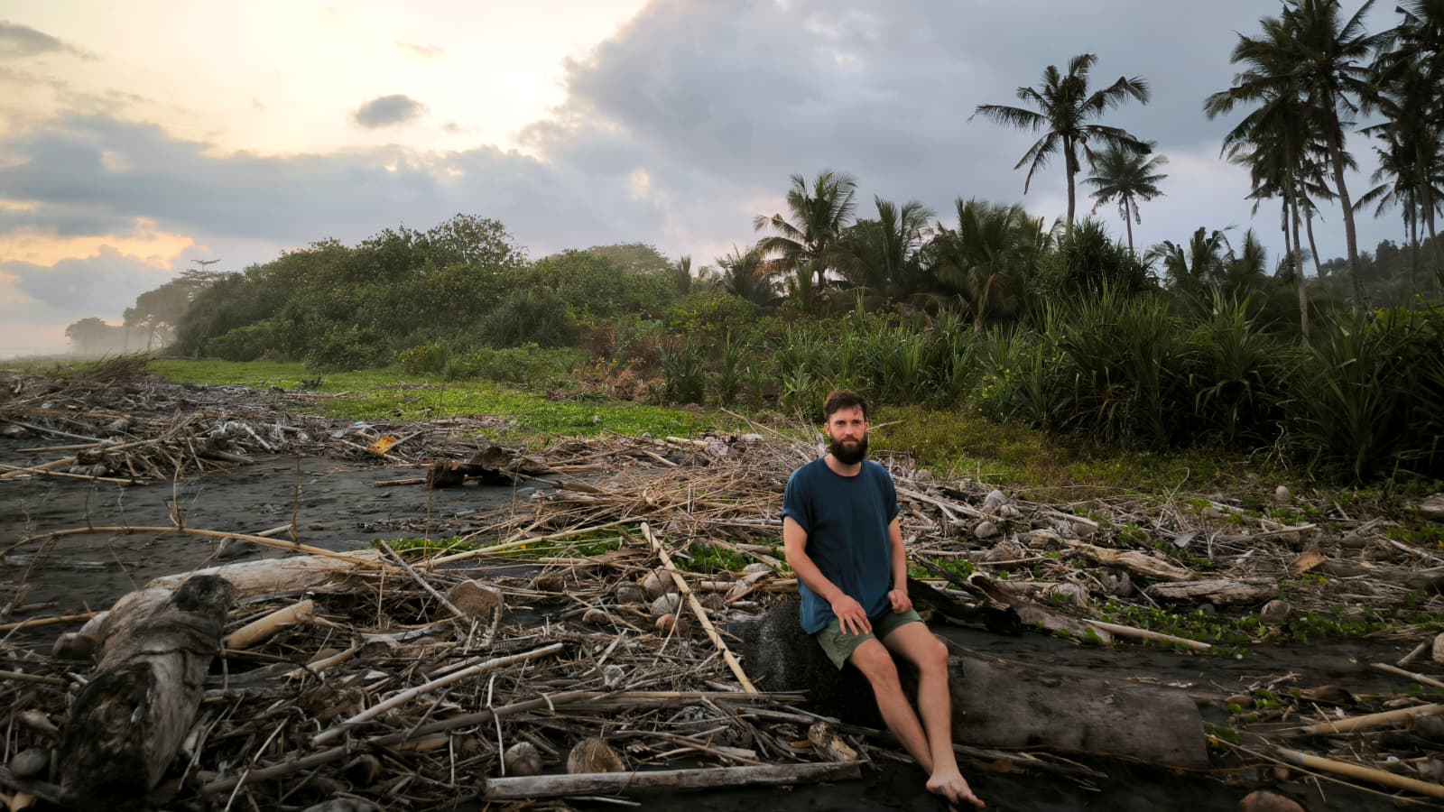 Hannes sitting quietly at dawn on a wild, driftwood-strewn shore